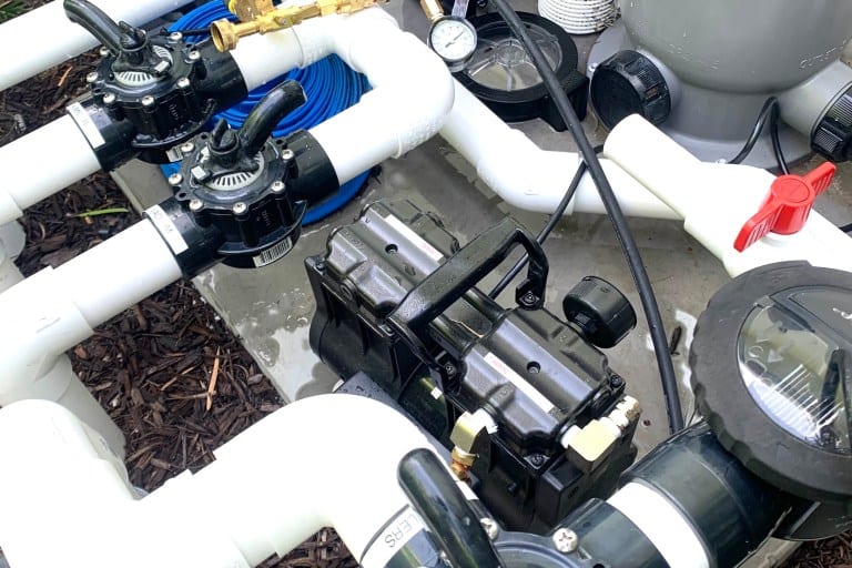 Pressure-testing rig connected to pool plumbing lines at the equipment pad